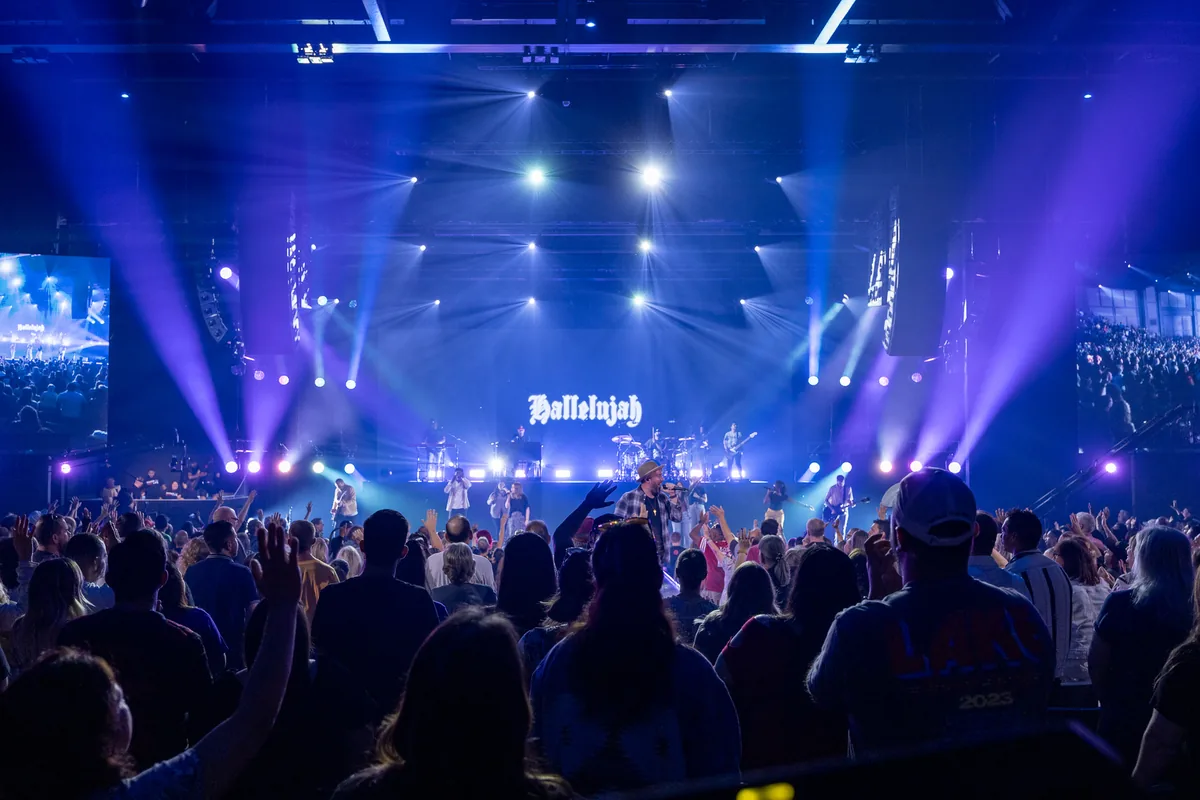 Arena concert with beams of stage light over the crowd