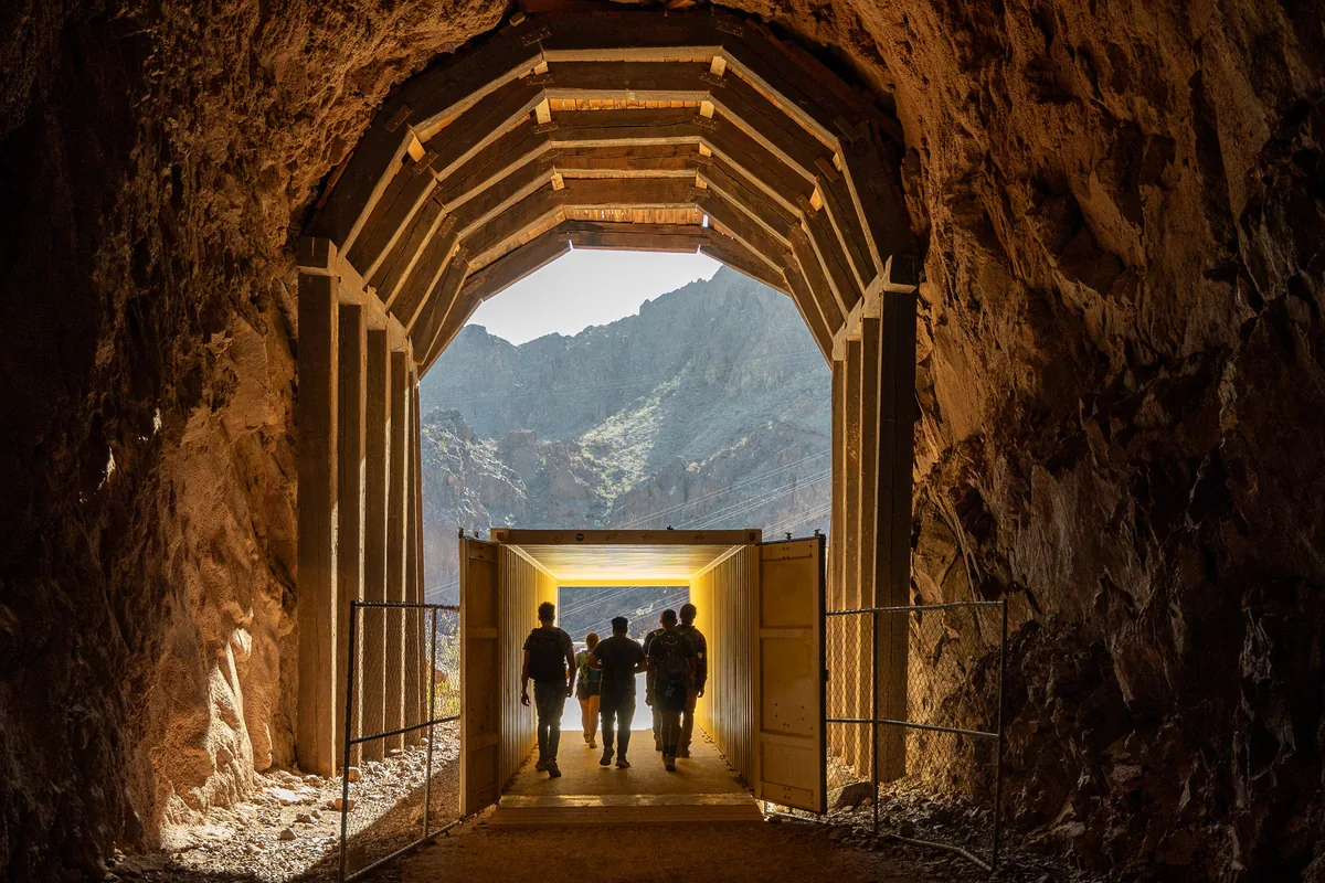 Hikers walking through a timber-lined tunnel
