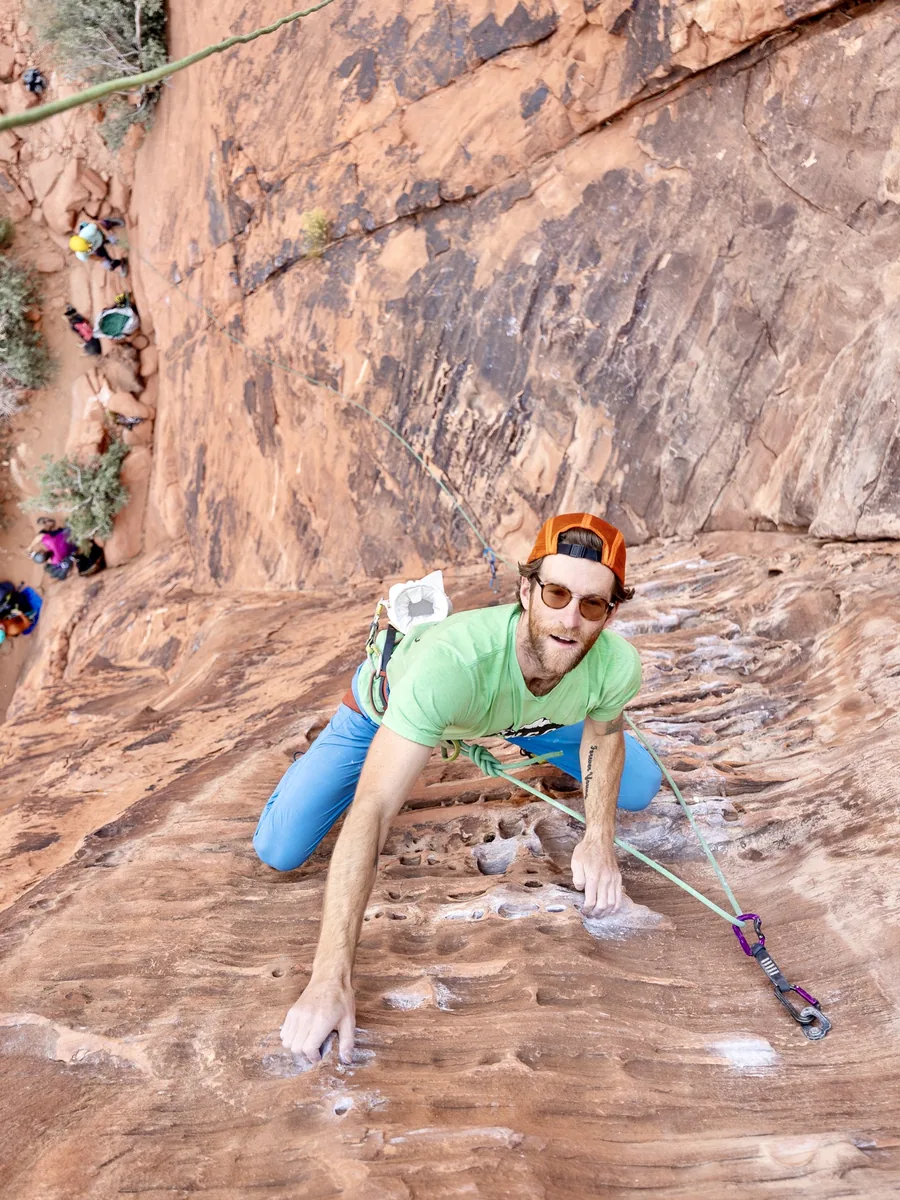 Climber smiling up at the camera mid-route