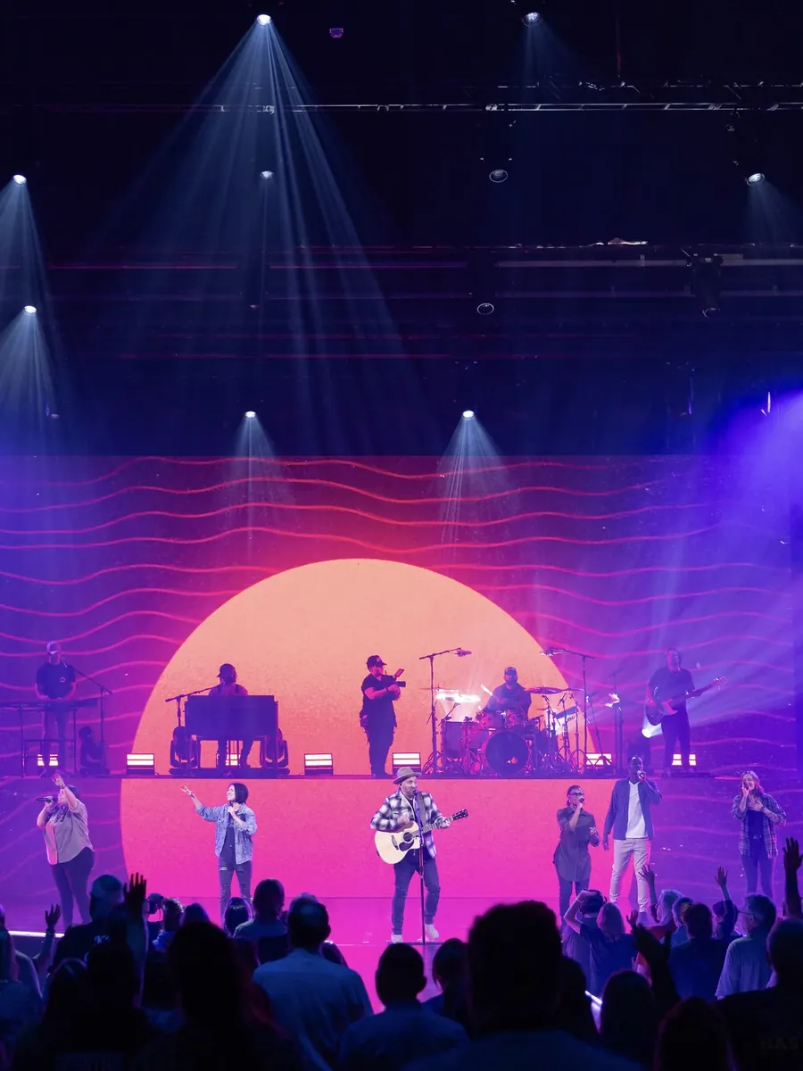 Band on stage in front of a glowing pink sun backdrop