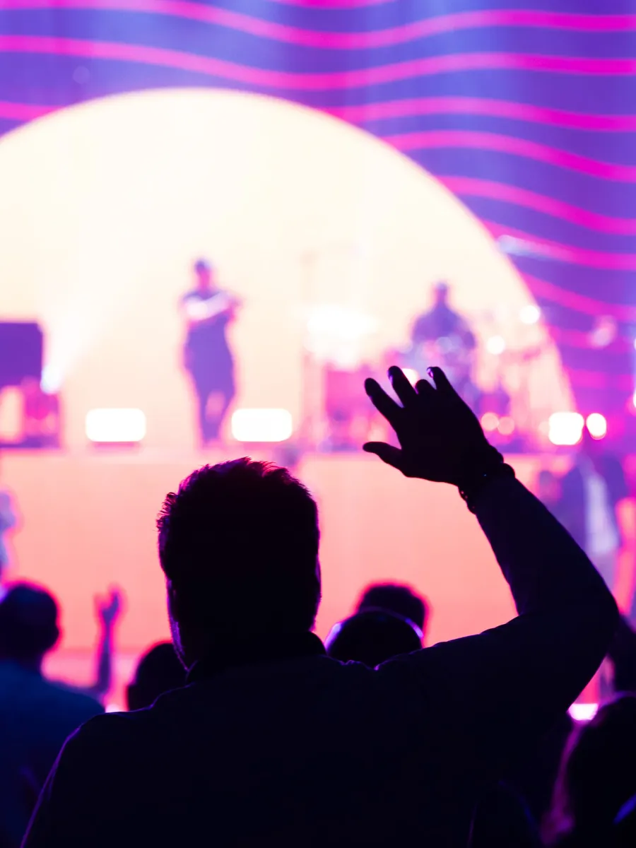 Silhouette of a raised hand against stage light